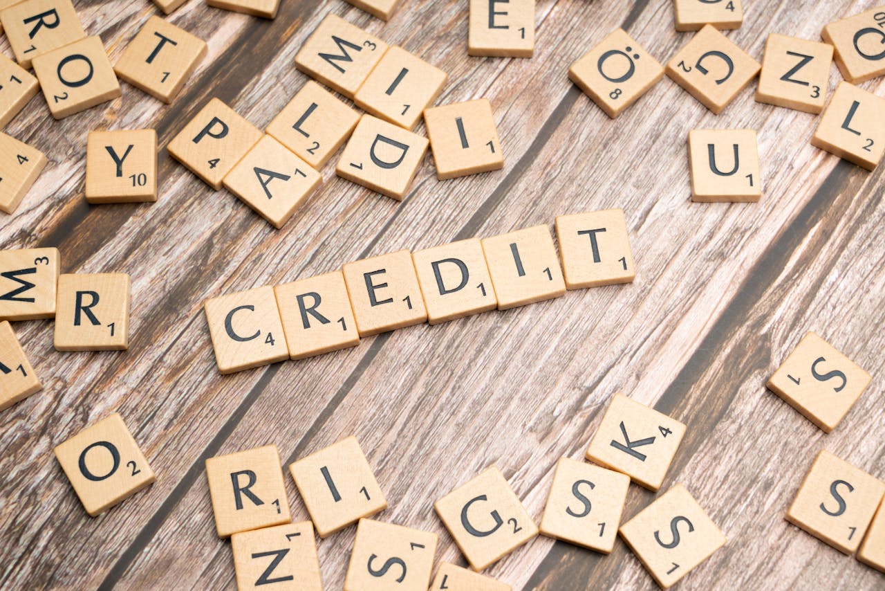 Wooden letter tiles arranged to spell CREDIT on a rustic table background.